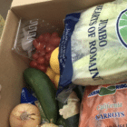 A hand reaching into a box of produce